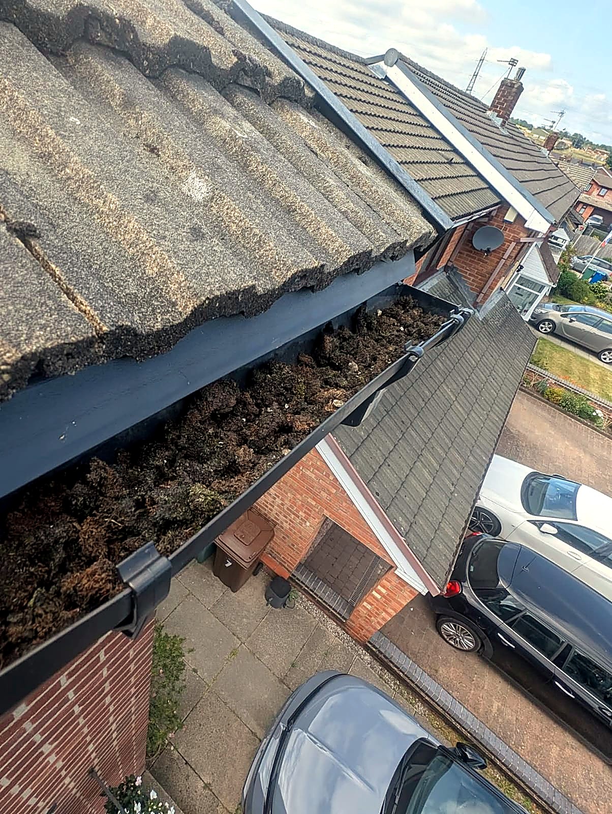 House gutter packed with moss and silt before gutter cleaning in Bury, Greater Manchester