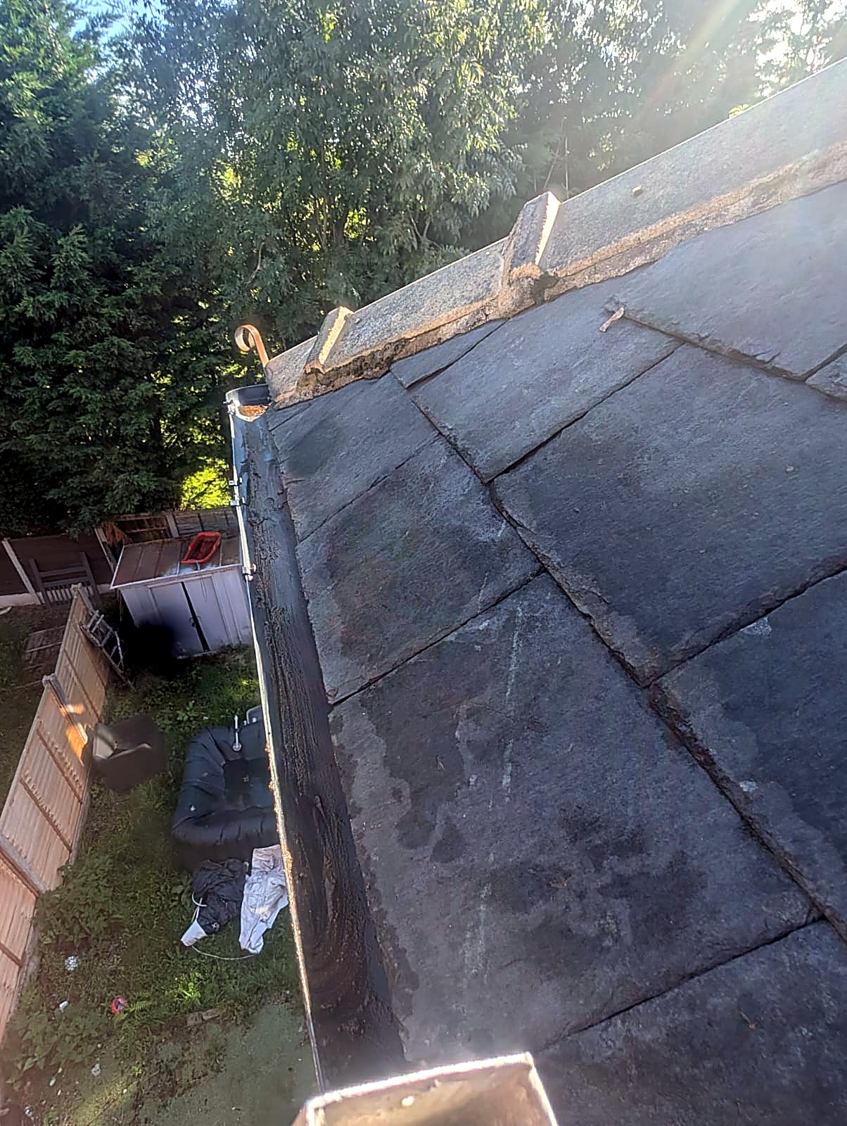Cleared gutter along a stone slate roof after gutter cleaning in Bury, Greater Manchester